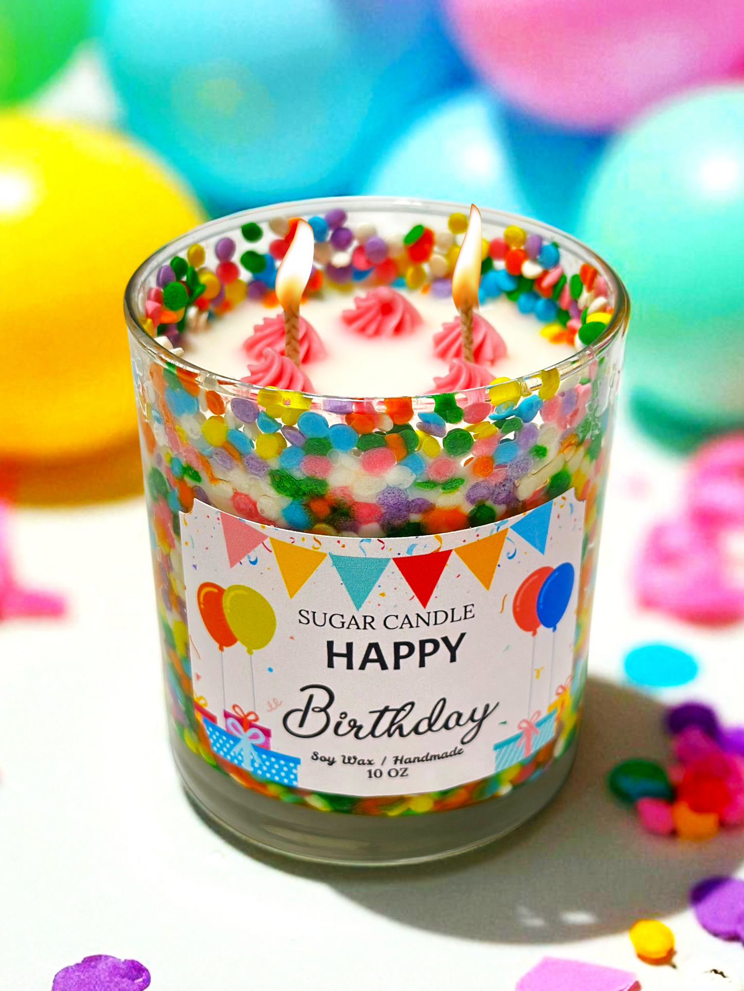 Birthday-themed candle with colorful sprinkles and a lit candle, surrounded by confetti and balloons.