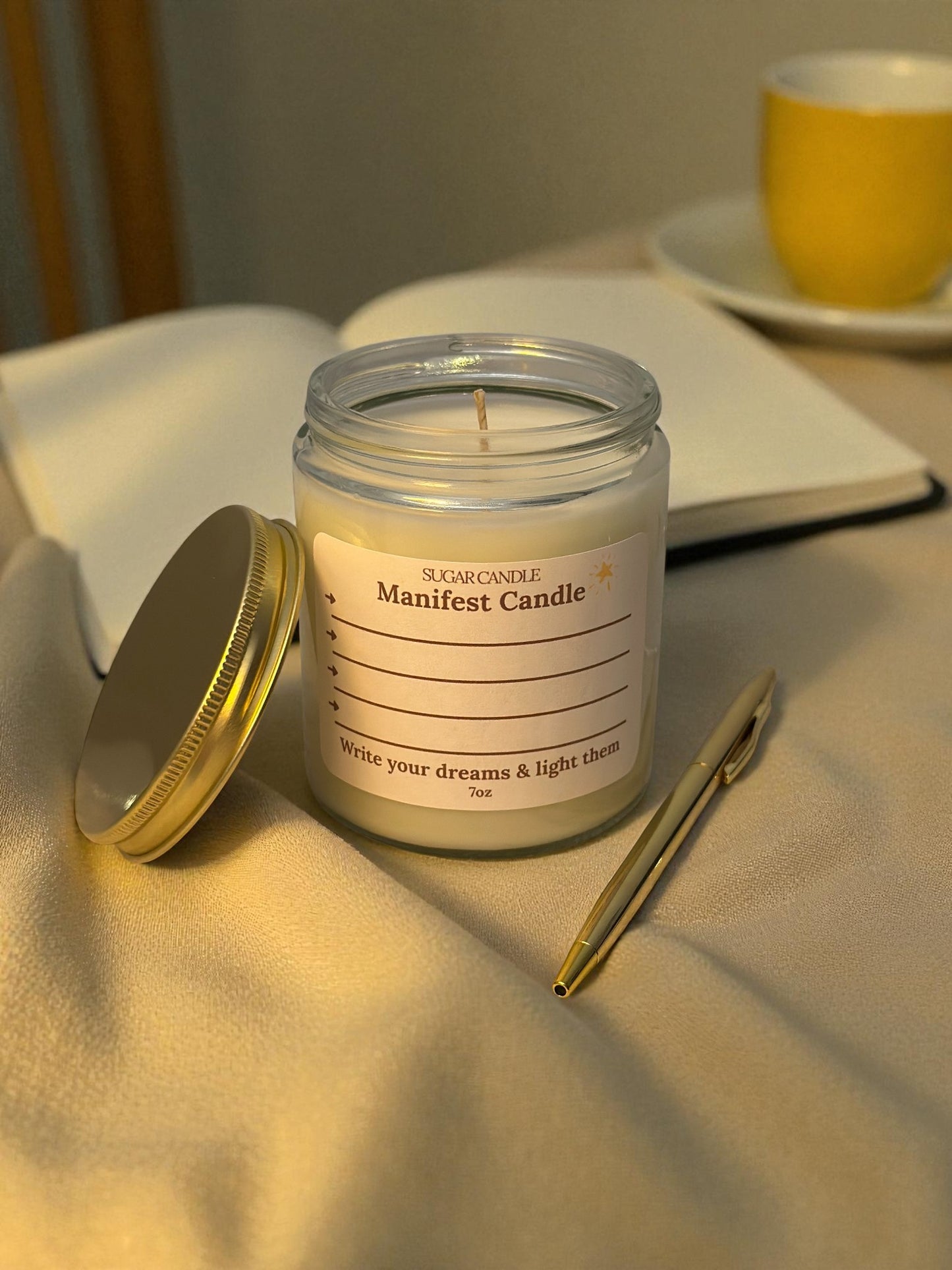 Manifest candle with a pen and notebook on a table