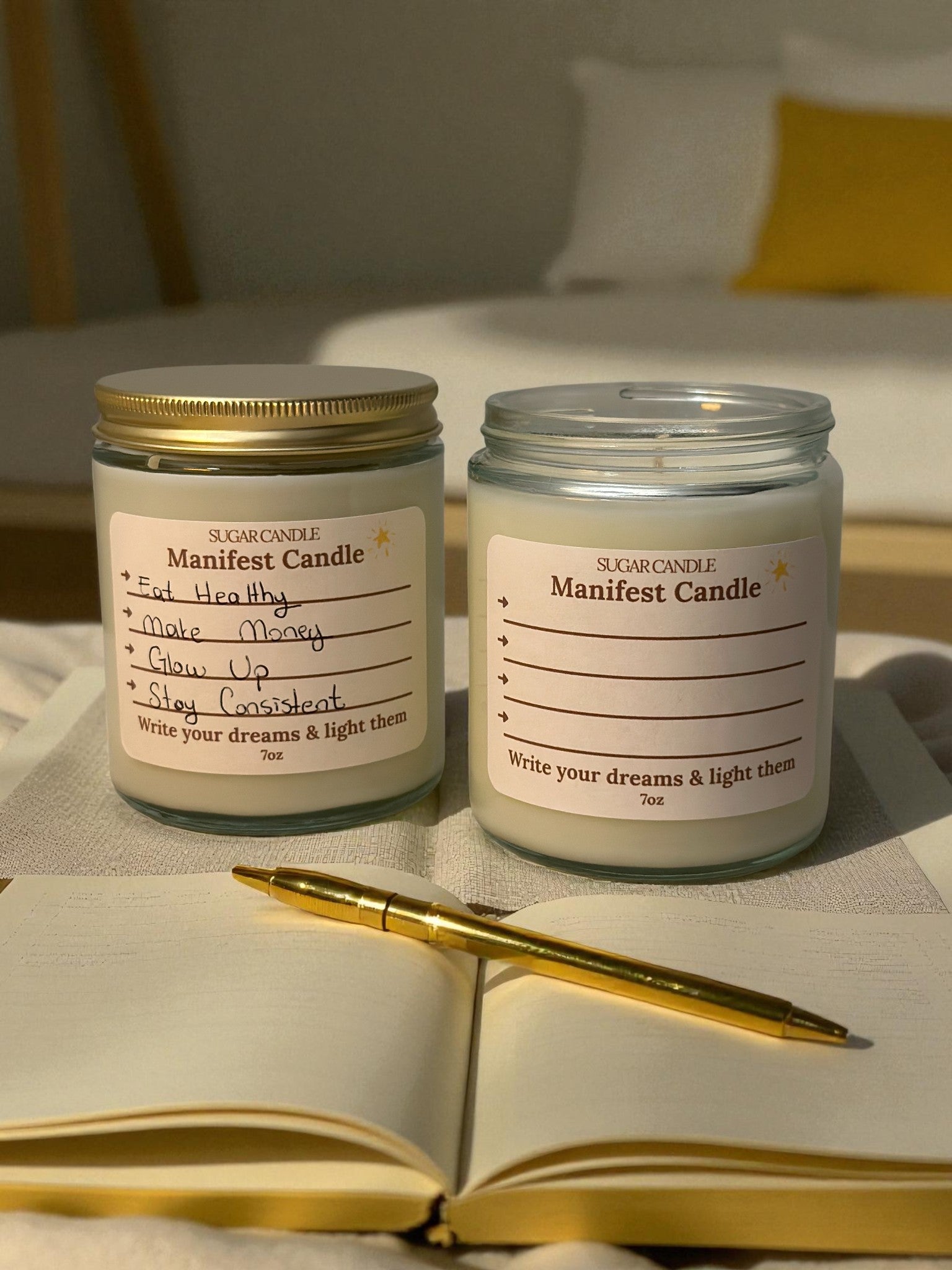 TwoManifest Candle jars on a surface with an open notebook and pen.