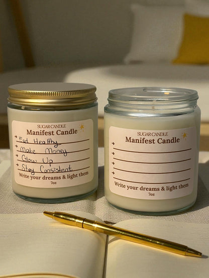 TwoManifest Candle jars on a surface with an open notebook and pen.