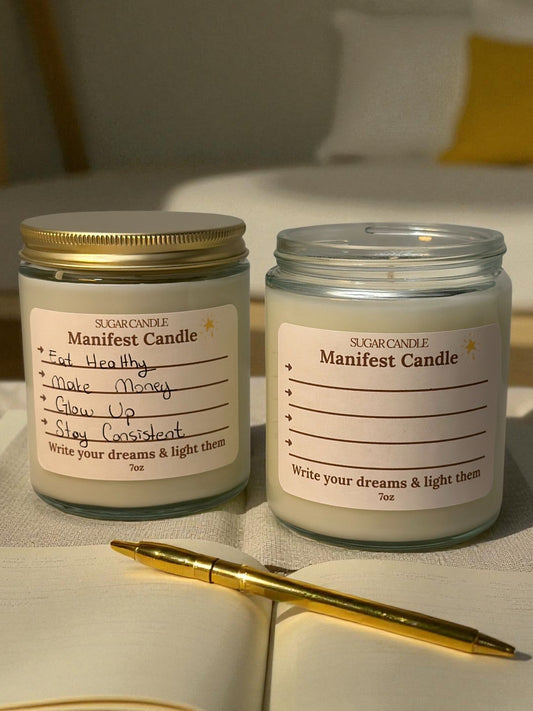 TwoManifest Candle jars on a surface with an open notebook and pen.