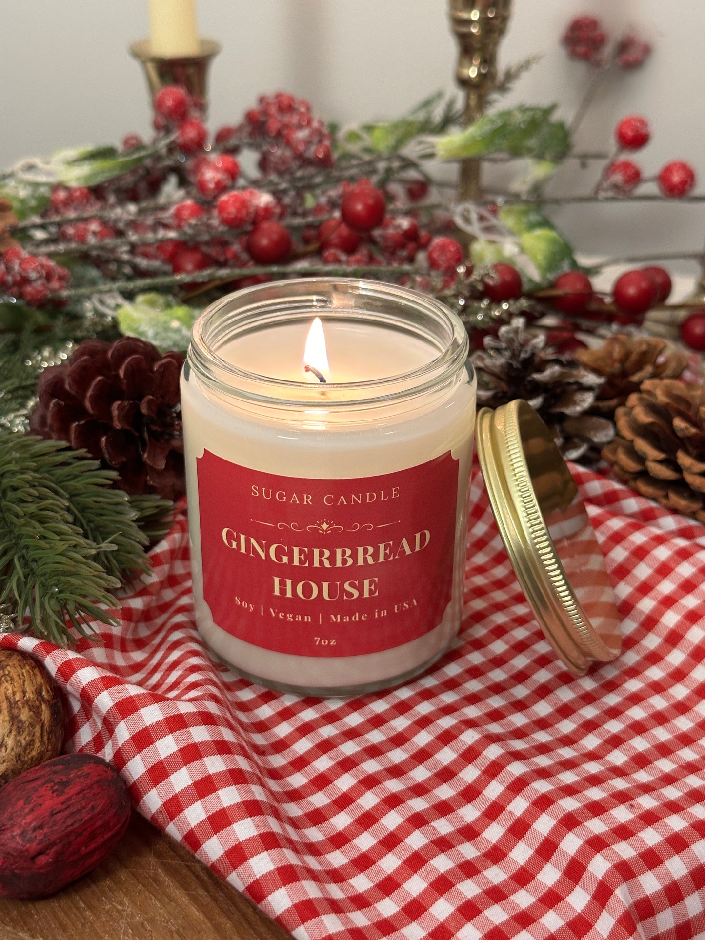 Gingerbread house candle with decorative elements on a checkered cloth