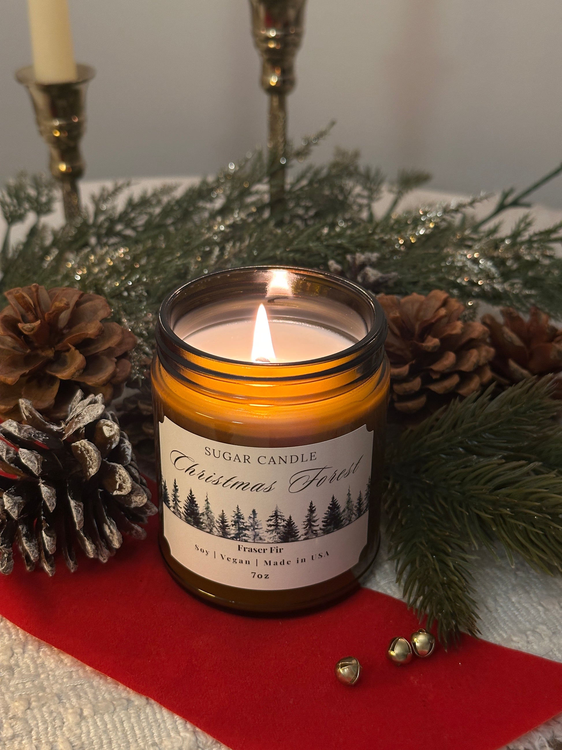 Candle in a jar with a label on a decorative surface with pine cones and greenery