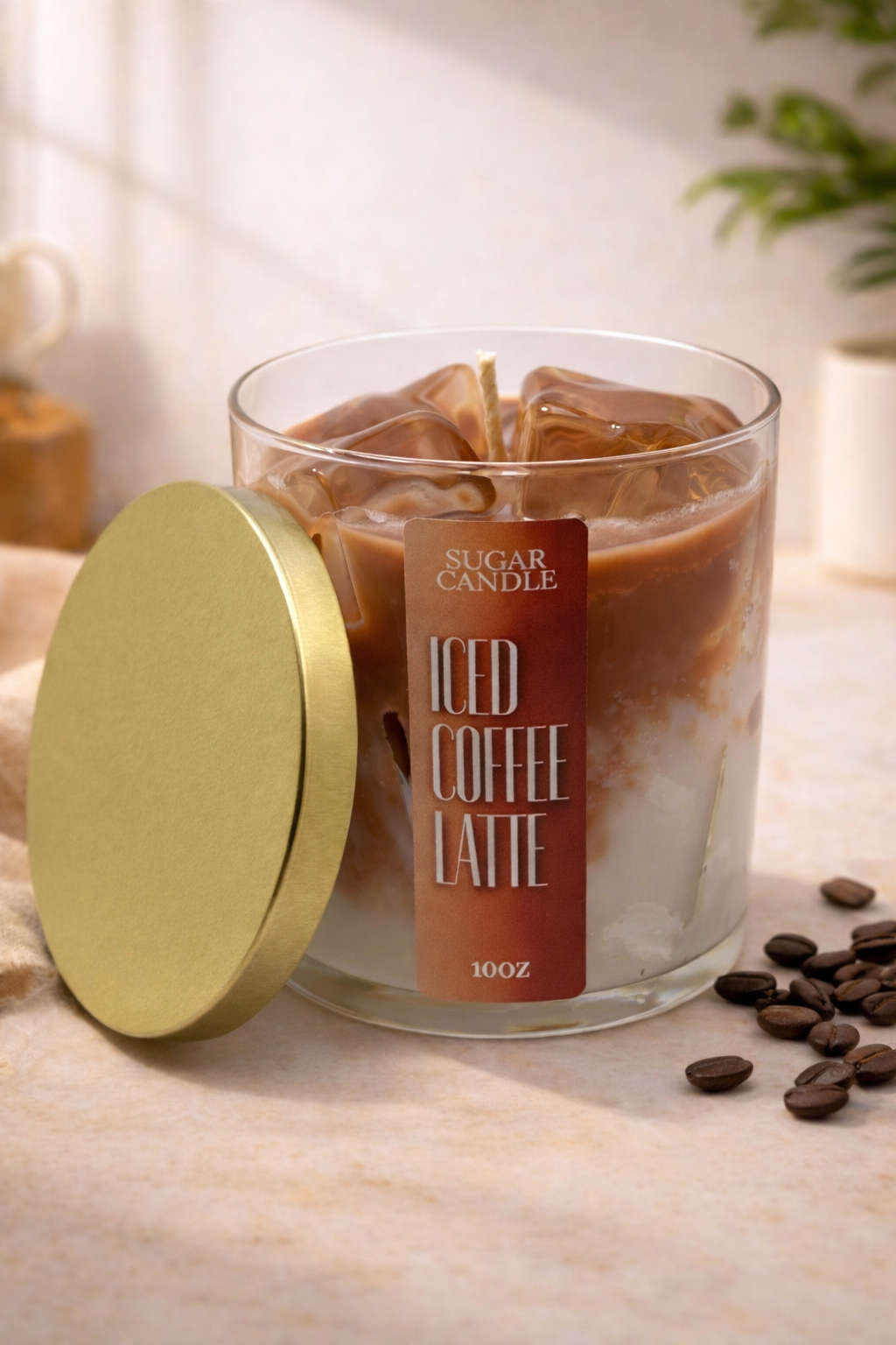 Glass candle labeled 'Iced Coffee Latte' with a gold lid on a light surface.