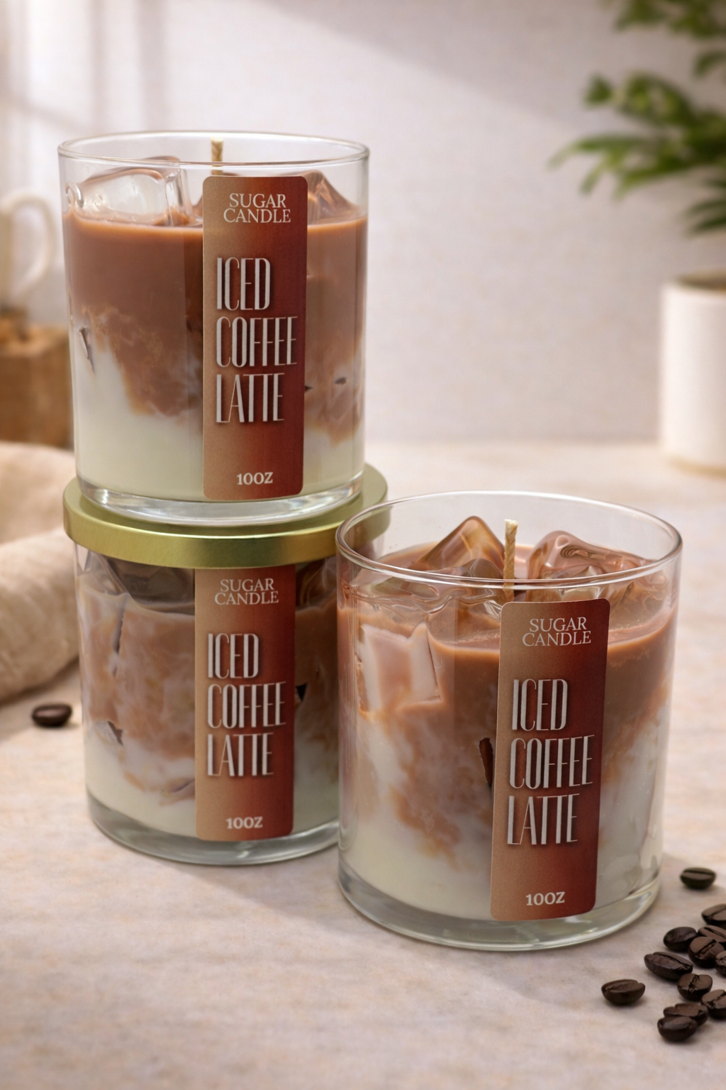 Candle labeled 'Iced Coffee Latte' in a glass container on a light surface with coffee beans.