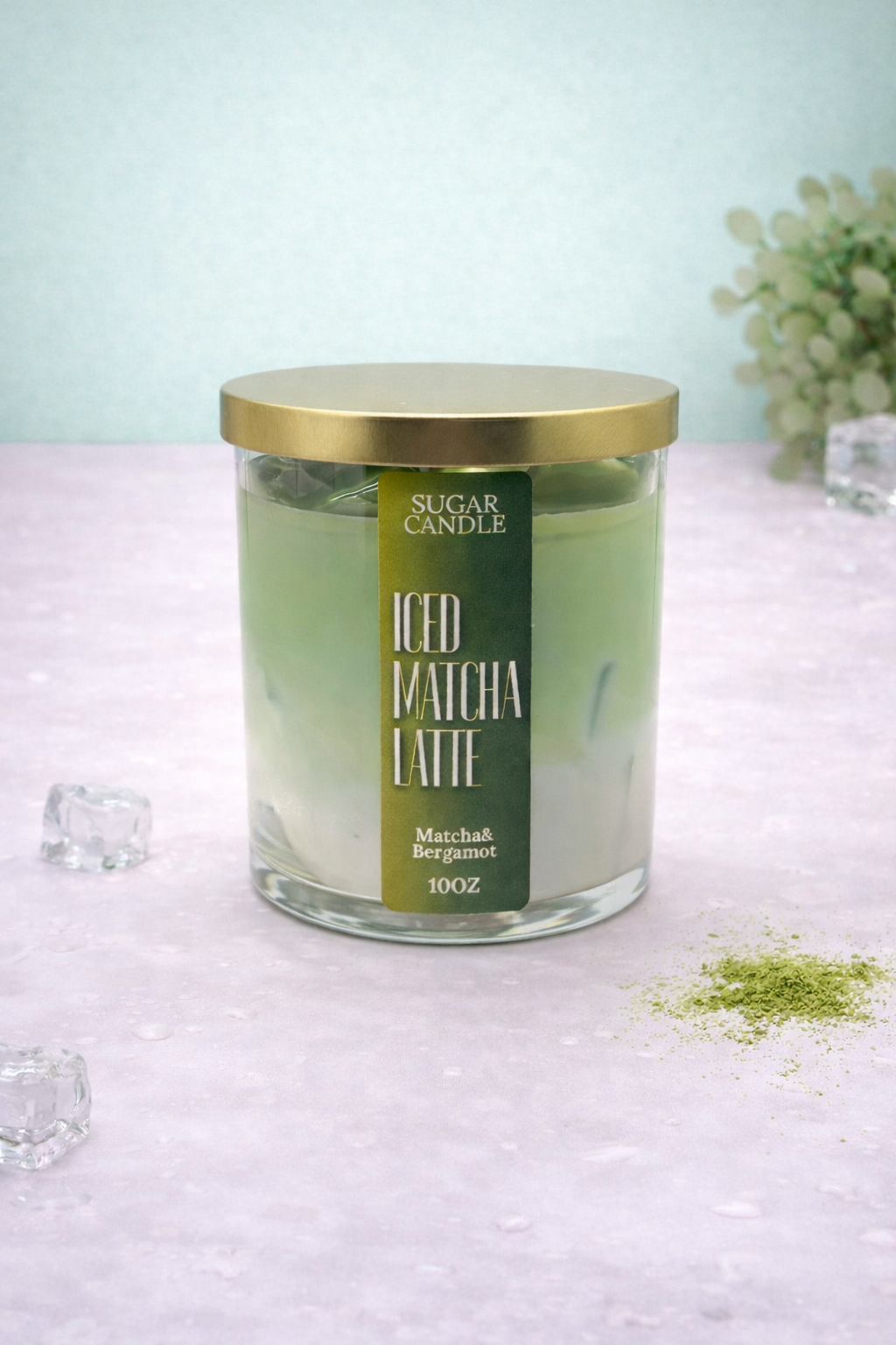 Glass candle with gold lid labeled 'Iced Matcha Latte' on a light surface.