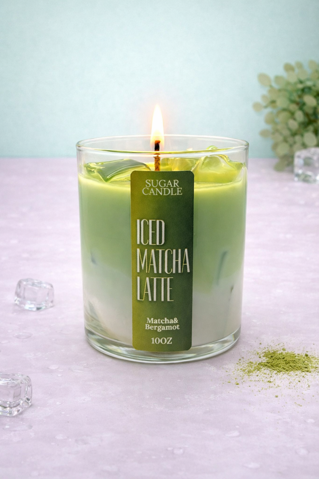 Green candle labeled 'Iced Matcha Latte' with a lit wick on a light surface.