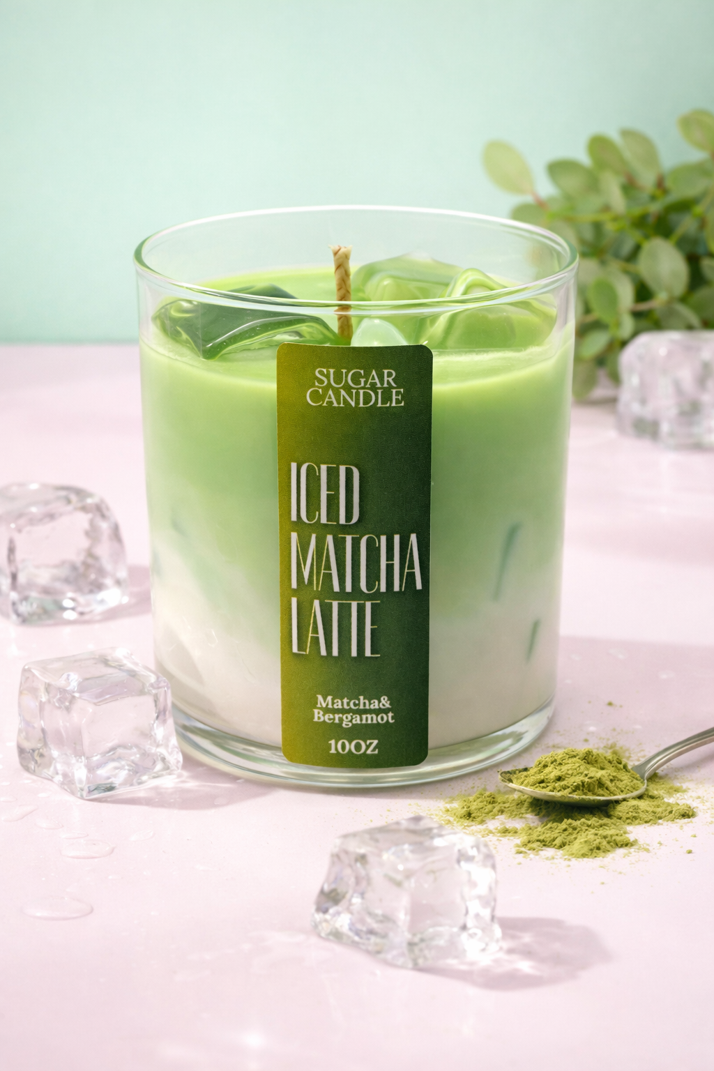 Green candle labeled 'ICED MATCHA LATTE' with matcha powder and ice cubes on a light pink surface.